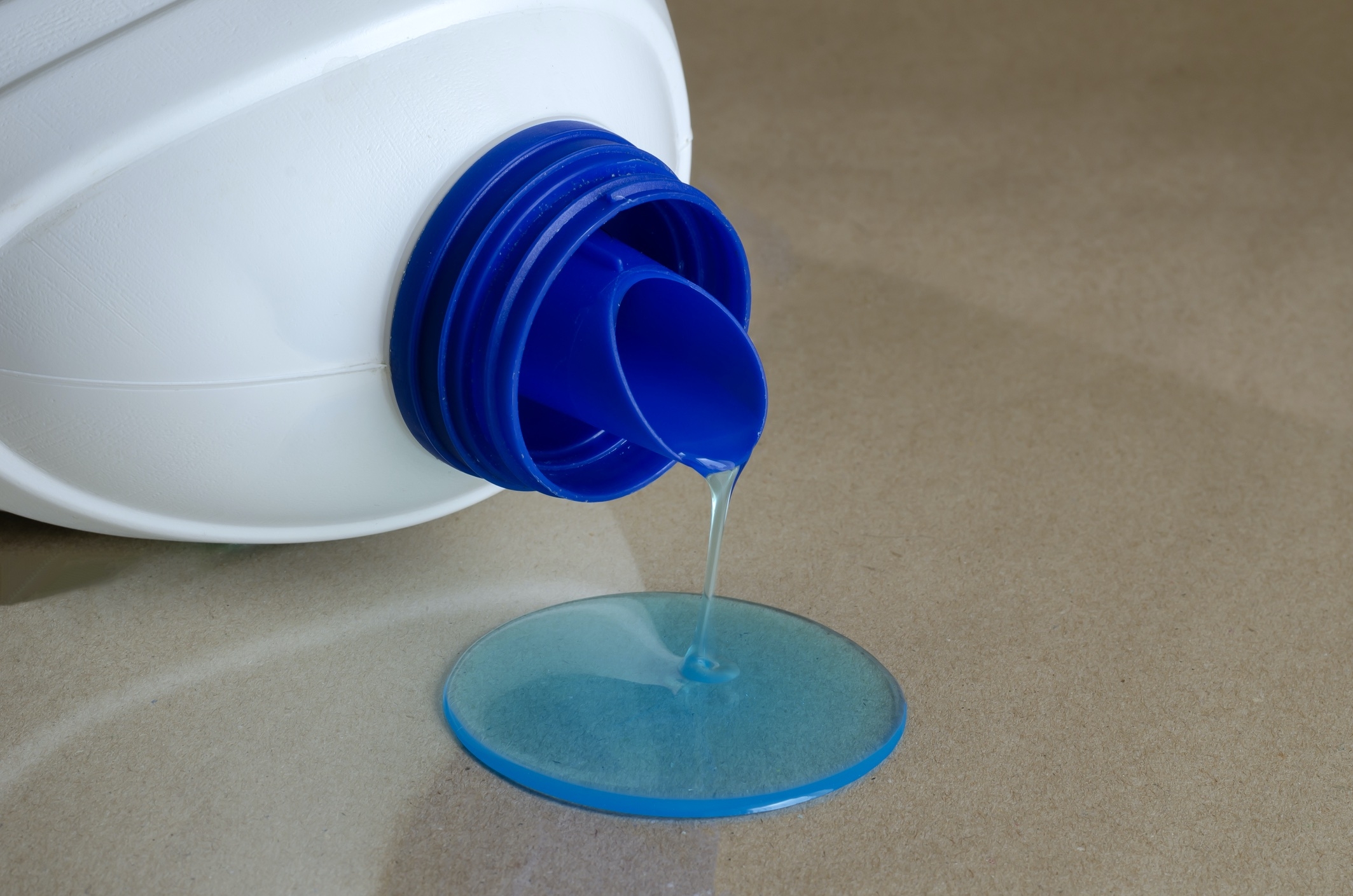 open bottle pouring out a small pool of detergent